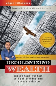 The image is the cover of the book "Decolonizing Wealth" by Edgar Villanueva. At the top, there is a red banner with the author's name in white text. Below, there is a forward by Bishop William J. Barber II. The main image shows a cityscape of tall buildings with a bird, possibly an eagle, soaring in the sky. On the left side of the image, there is a photo of the author, Edgar Villanueva, smiling and crossing his arms. To the right, there is a yellow circle with a quote: "...a pathway to healing that we all need." by Dawn K. Robinson. Below the image, a black banner with yellow text indicates this is the "second edition, revised and expanded." The book title "Decolonizing Wealth" is in large white text on a red background. At the bottom, a gray banner with black text describes the book as "indigenous wisdom to heal divides and restore balance."